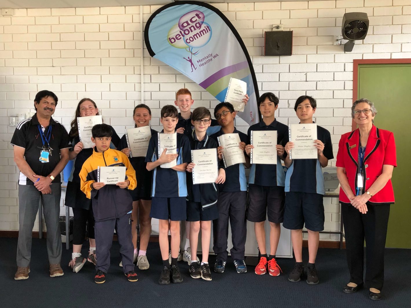 9 students holding certificates with two teachers next to them