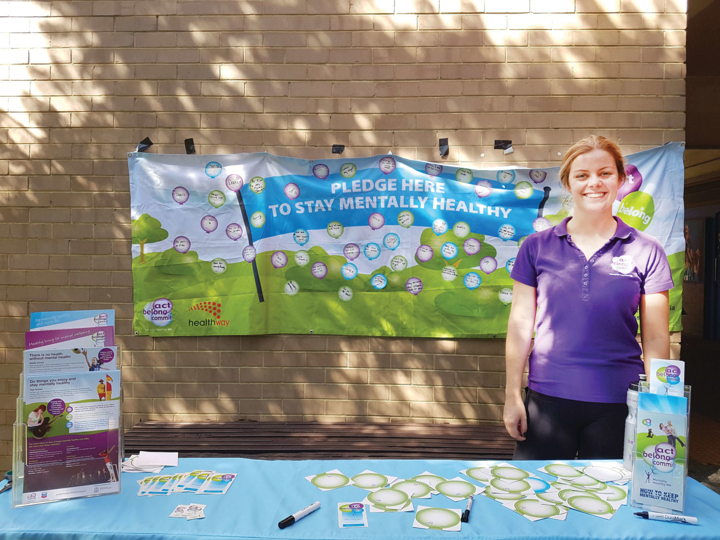 girl in purple shirt attends a stall with sign behind her