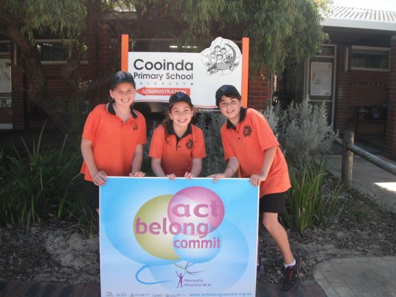 three students standing behind sign