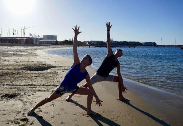 wan and woman doing yoga on beach