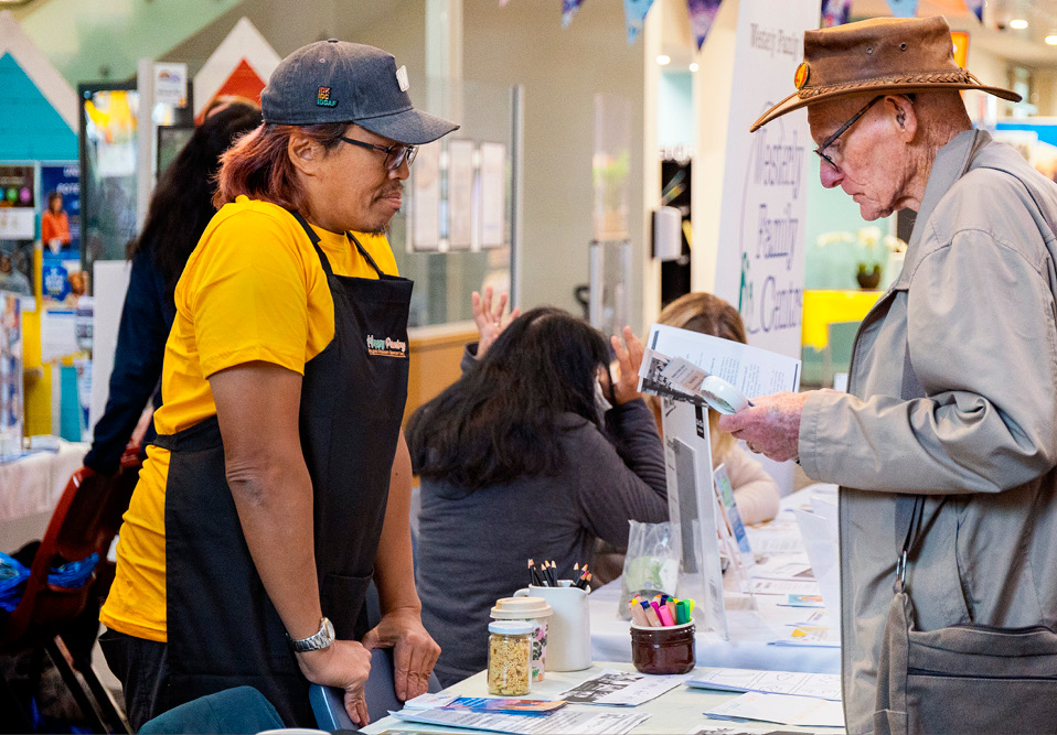 Two people standing across from each other. One is looking at a leaflet.
